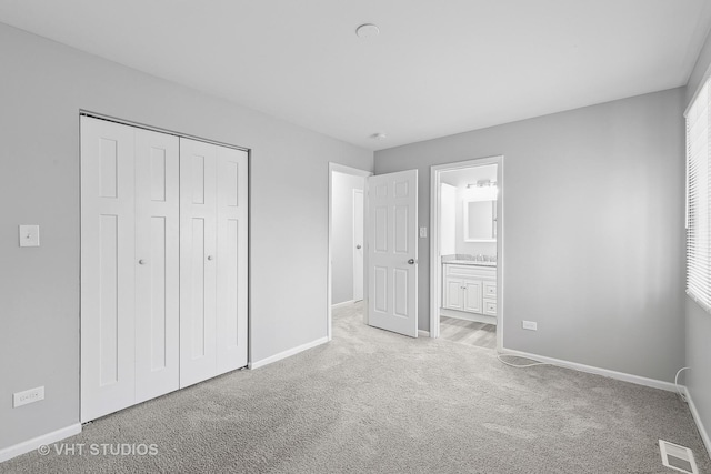 unfurnished bedroom with light carpet, ensuite bath, and a closet