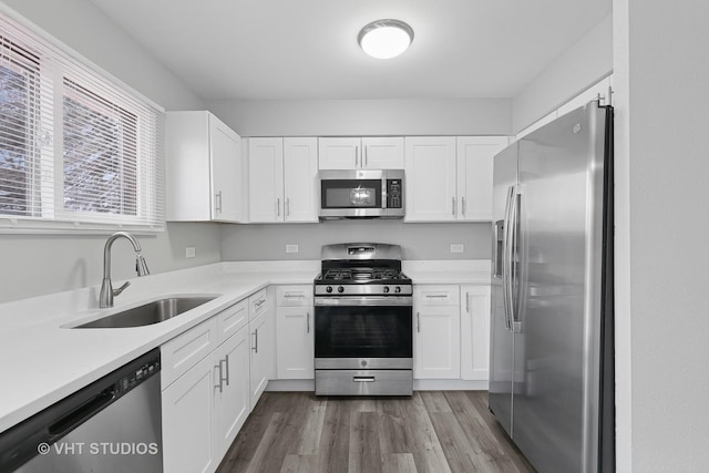 kitchen featuring white cabinetry, sink, hardwood / wood-style floors, and appliances with stainless steel finishes