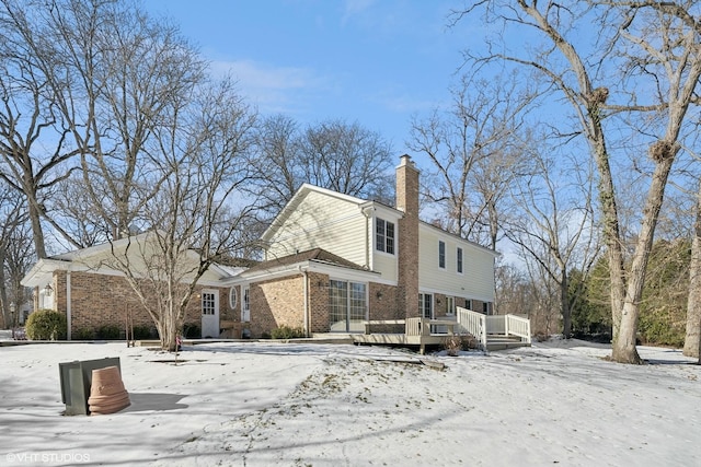 snow covered back of property with a wooden deck