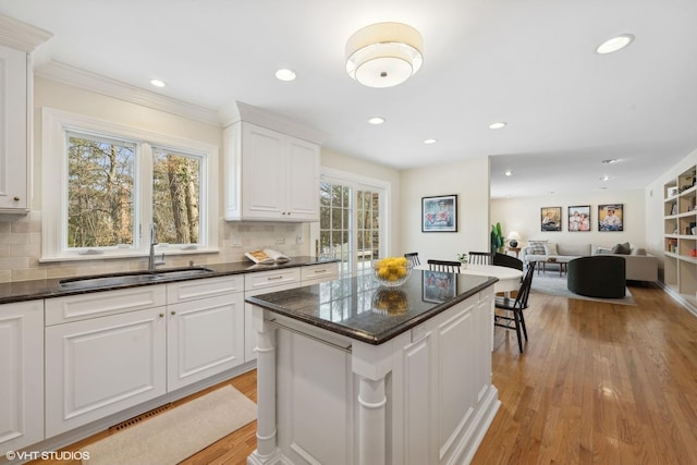 kitchen featuring a center island, sink, decorative backsplash, and white cabinets