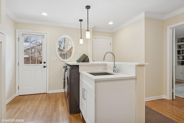 laundry room with crown molding, sink, and light wood-type flooring