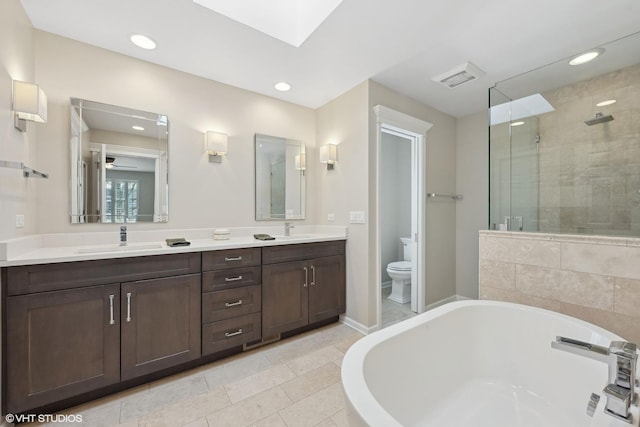 full bathroom with toilet, shower with separate bathtub, vanity, and a skylight