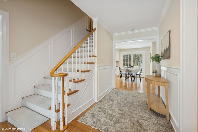 stairway with crown molding and hardwood / wood-style floors