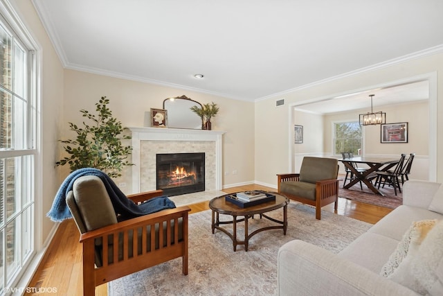 living room featuring a fireplace, crown molding, light hardwood / wood-style flooring, and a healthy amount of sunlight