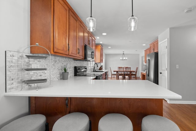 kitchen with kitchen peninsula, range with electric cooktop, stainless steel fridge, and pendant lighting