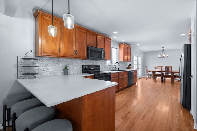 kitchen featuring stainless steel fridge, kitchen peninsula, decorative light fixtures, dishwasher, and black range with electric cooktop