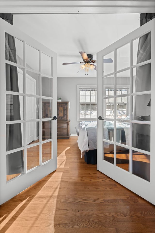 unfurnished bedroom featuring ceiling fan, wood-type flooring, and french doors