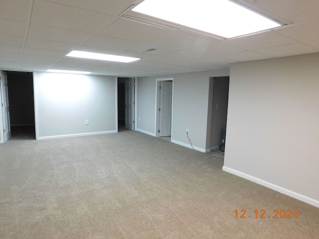 basement featuring light carpet and a drop ceiling