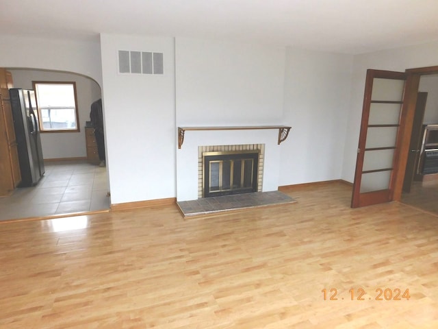 unfurnished living room featuring a fireplace and light hardwood / wood-style floors