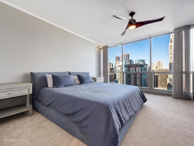 carpeted bedroom featuring ceiling fan, multiple windows, a wall of windows, and ornamental molding