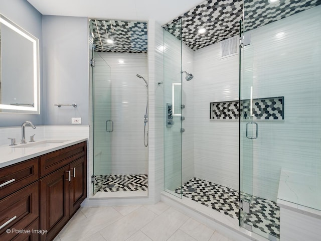 bathroom with a shower with door, tile patterned floors, and vanity