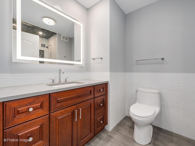 bathroom featuring toilet, vanity, tile walls, walk in shower, and tile patterned floors