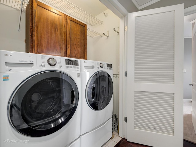 clothes washing area with washer and dryer, cabinets, and light tile patterned flooring