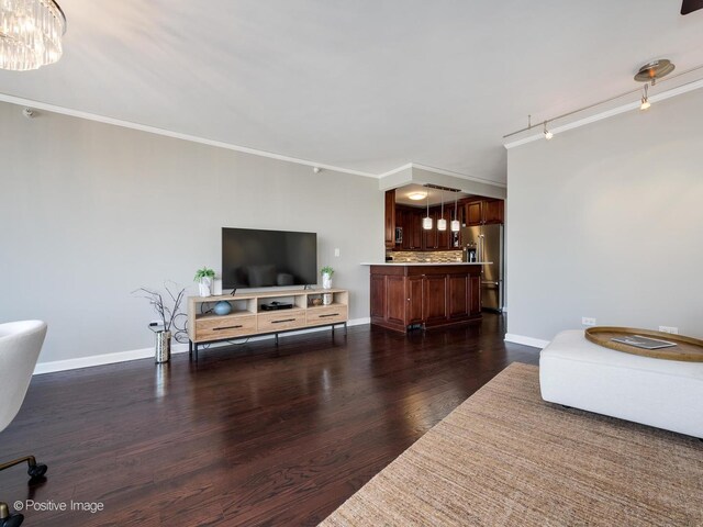 living room featuring dark wood-type flooring, crown molding, and rail lighting