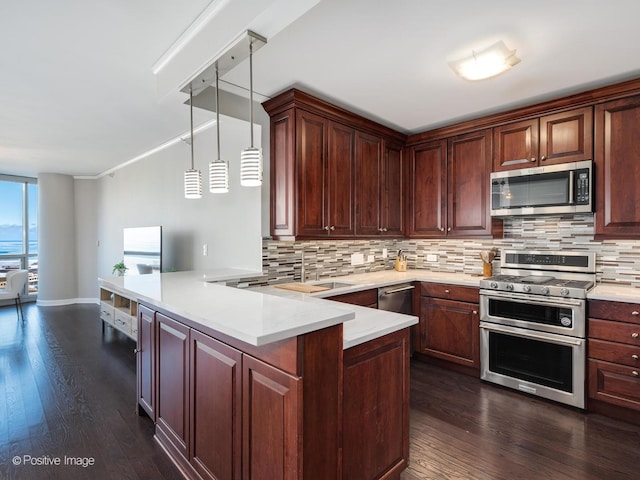 kitchen with dark hardwood / wood-style floors, kitchen peninsula, sink, hanging light fixtures, and stainless steel appliances