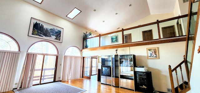 kitchen featuring high vaulted ceiling, wine cooler, and light wood-type flooring