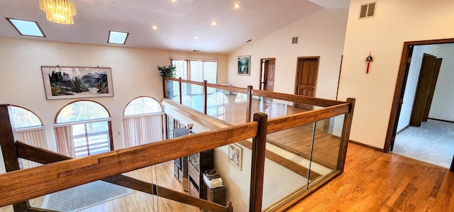 hall with a chandelier, lofted ceiling, and light hardwood / wood-style flooring