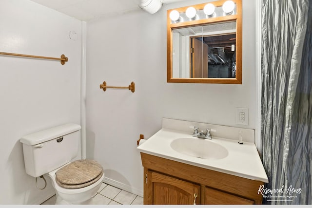 bathroom with toilet, vanity, and tile patterned floors