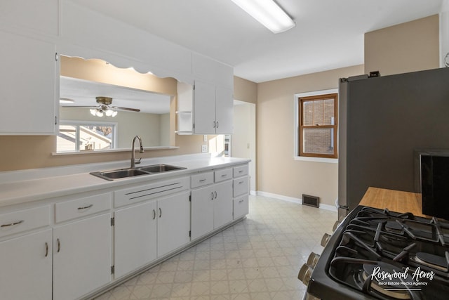 kitchen with ceiling fan, sink, white cabinetry, and stainless steel appliances