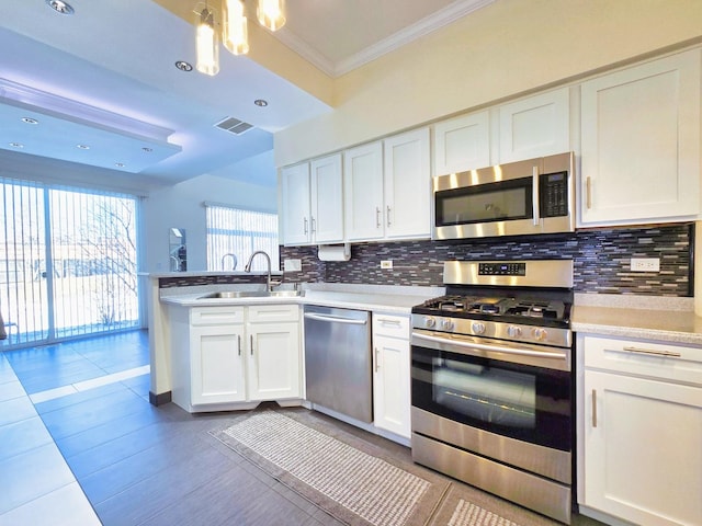 kitchen with sink, ornamental molding, appliances with stainless steel finishes, decorative backsplash, and white cabinets