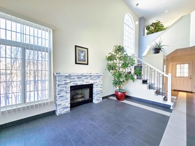 living room featuring dark tile patterned floors, a stone fireplace, and a high ceiling