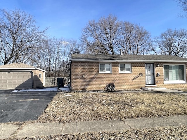 view of front of property with a garage, brick siding, an outbuilding, and fence