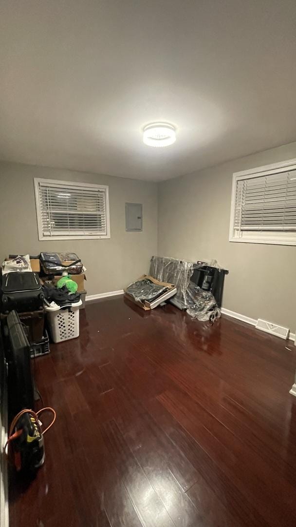 interior space featuring electric panel, visible vents, baseboards, and wood finished floors