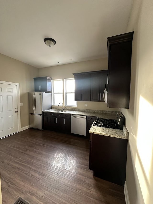 kitchen with light stone countertops, dark wood-type flooring, stainless steel appliances, and sink