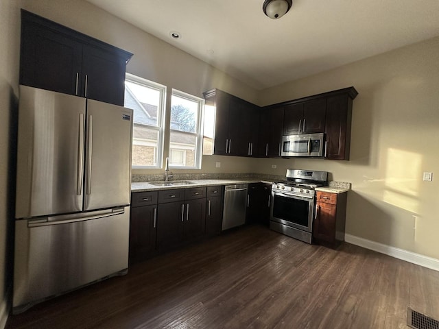 kitchen with dark hardwood / wood-style flooring, sink, light stone counters, and stainless steel appliances