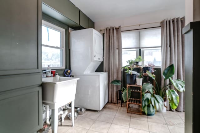 laundry room with a wealth of natural light, light tile patterned floors, and stacked washer and clothes dryer