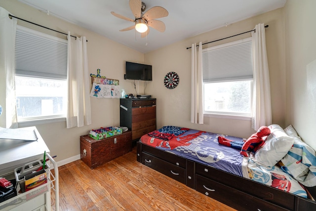 bedroom with ceiling fan, light hardwood / wood-style floors, and multiple windows