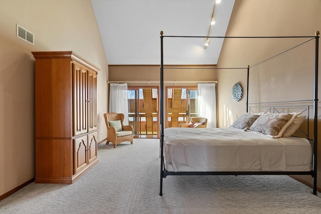 carpeted bedroom with track lighting and high vaulted ceiling