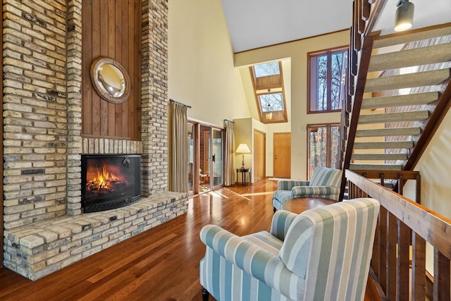 living room with a fireplace, a skylight, hardwood / wood-style floors, and a high ceiling