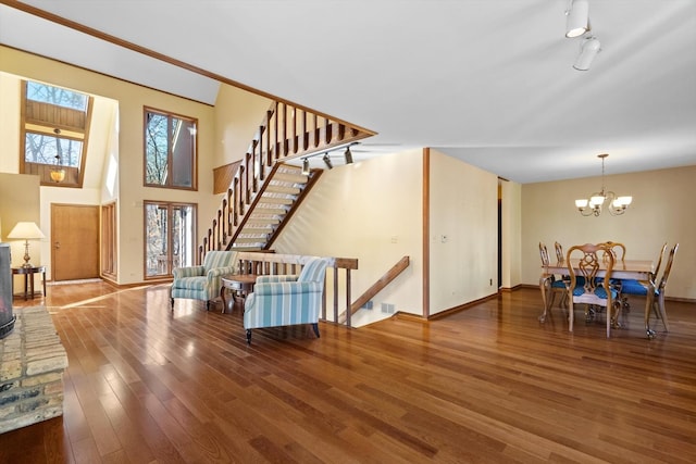 living room featuring hardwood / wood-style floors, a notable chandelier, track lighting, and a towering ceiling