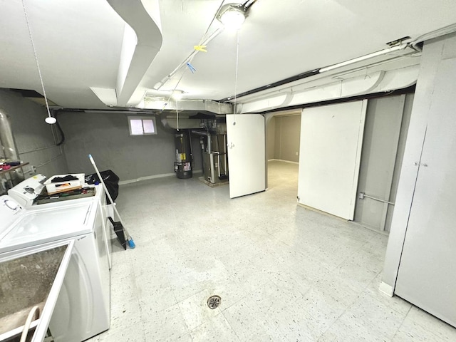 clothes washing area featuring heating unit, electric water heater, and washer and dryer