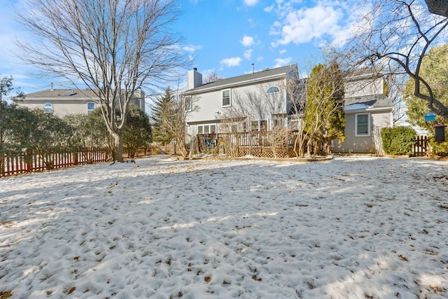 snow covered house with a wooden deck