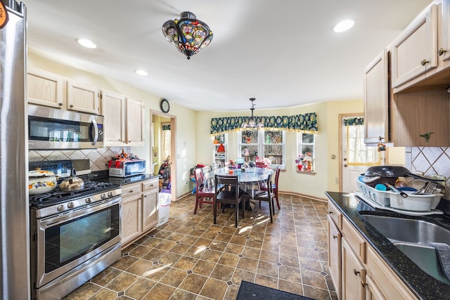 kitchen featuring pendant lighting, stainless steel appliances, tasteful backsplash, light brown cabinetry, and sink