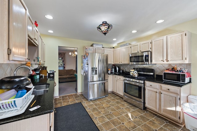 kitchen with appliances with stainless steel finishes, light brown cabinets, an inviting chandelier, sink, and backsplash