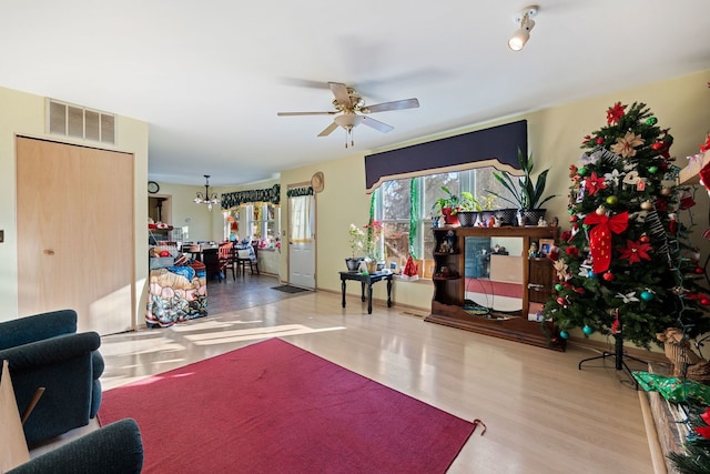 living room featuring hardwood / wood-style flooring and ceiling fan with notable chandelier