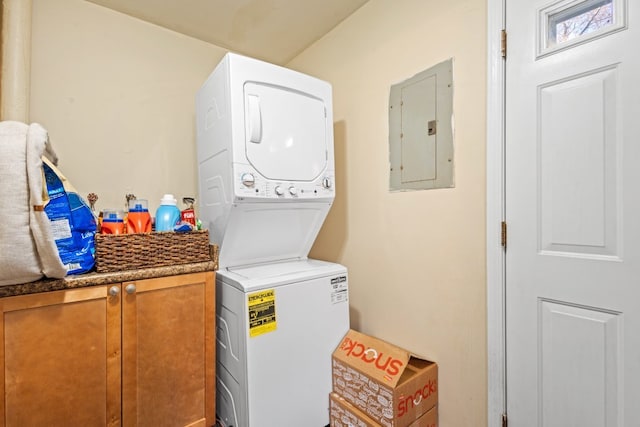 laundry room with cabinets, electric panel, and stacked washer / drying machine