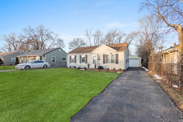 view of front of property featuring a front yard, a garage, and an outbuilding