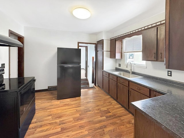 kitchen with sink, light hardwood / wood-style floors, dark brown cabinetry, and black appliances