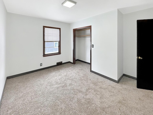 unfurnished bedroom with light colored carpet and a closet