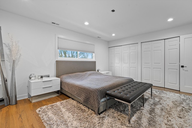 bedroom with two closets and light wood-type flooring