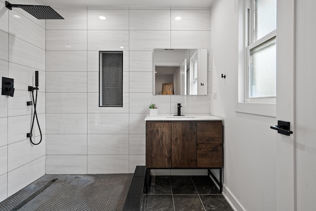 bathroom with tile patterned flooring, vanity, and a tile shower