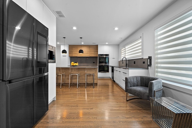 kitchen with pendant lighting, sink, appliances with stainless steel finishes, white cabinets, and dark hardwood / wood-style flooring