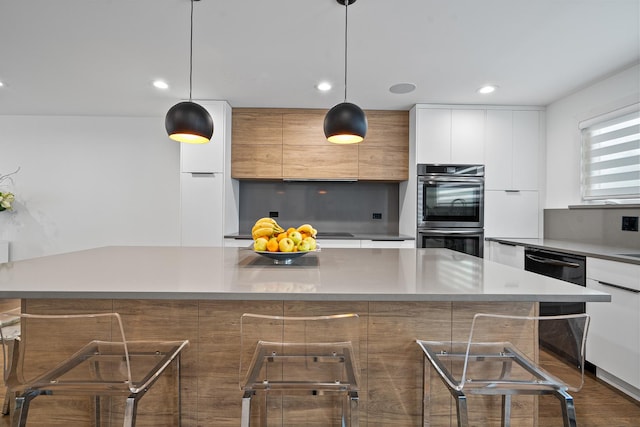 kitchen with stainless steel double oven, a kitchen island, hanging light fixtures, and white cabinets