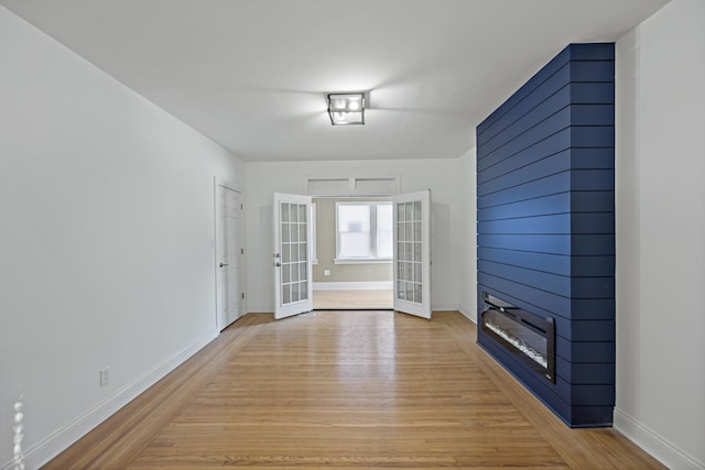 unfurnished living room with light wood-type flooring, a fireplace, and french doors