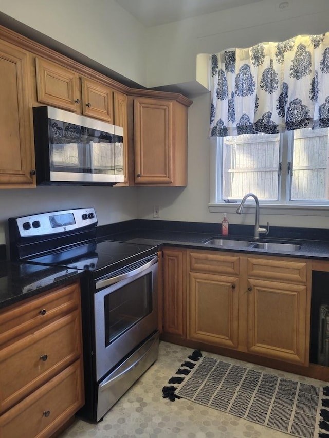 kitchen featuring stainless steel appliances, dark stone countertops, and sink