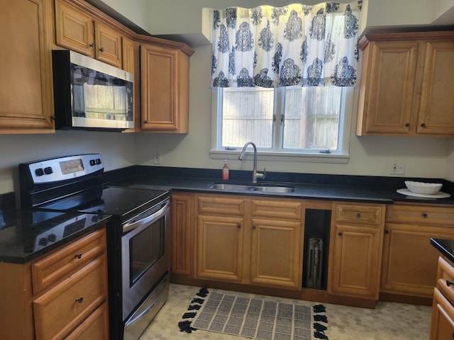 kitchen featuring sink, appliances with stainless steel finishes, and dark stone countertops